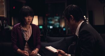 Movie still from “Babel” (2006), directed by Alejandro G. Iñárritu – A man and a woman sitting on a couch in front of each other; Medium shot, Over the shoulder angle