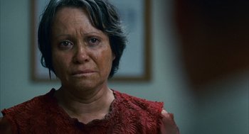Movie still from “Babel” (2006), directed by Alejandro G. Iñárritu – An older woman in a red dress looking at the camera; Close Up shot, Over the shoulder angle