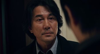 Movie still from “Babel” (2006), directed by Alejandro G. Iñárritu – A person wearing a suit and tie; Close Up shot, Over the shoulder angle