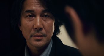Movie still from “Babel” (2006), directed by Alejandro G. Iñárritu – A person wearing a suit and tie; Close Up shot, Over the shoulder angle