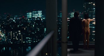 Movie still from “Babel” (2006), directed by Alejandro G. Iñárritu – A man standing on a balcony overlooking a city at night; Wide shot, Over the shoulder angle