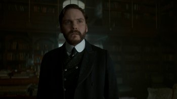 Movie still from “The Alienist” (2018), created by Cary Joji Fukunaga – A man in a suit and tie standing in a room; Close Up shot, Low angle