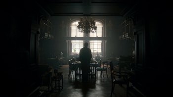 Movie still from “The Alienist” (2018), created by Cary Joji Fukunaga – A man standing in front of a window in a room; Extreme Wide shot, Low angle