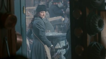 Movie still from “The Alienist” (2018), created by Cary Joji Fukunaga – A woman standing next to an old newspaper box; Medium shot, Over the shoulder angle