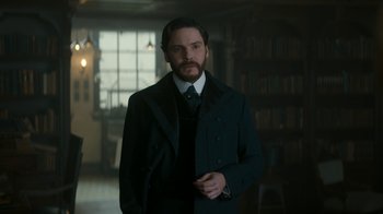 Movie still from “The Alienist” (2018), created by Cary Joji Fukunaga – A man with a beard wearing a suit and tie; Medium shot, Over the shoulder angle
