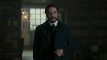 Movie still from “The Alienist” (2018), created by Cary Joji Fukunaga – A man with a beard wearing a suit and tie; Medium shot, Low angle