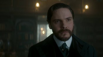Movie still from “The Alienist” (2018), created by Cary Joji Fukunaga – A person wearing a suit and tie; Close Up shot, Low angle