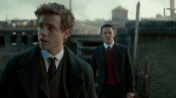 Movie still from “The Alienist” (2018), created by Cary Joji Fukunaga – Two men in suits and ties standing next to each other; Close Up shot, Over the shoulder angle