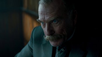 Movie still from “The Alienist” (2018), created by Cary Joji Fukunaga – An older man with a beard and mustache wearing a suit and tie; Close Up shot, Over the shoulder angle
