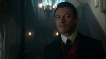 Movie still from “The Alienist” (2018), created by Cary Joji Fukunaga – A man wearing a suit and tie in a room; Close Up shot, Over the shoulder angle