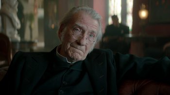 Movie still from “The Alienist” (2018), created by Cary Joji Fukunaga – An old man with glasses sitting in a chair; Close Up shot, Over the shoulder angle