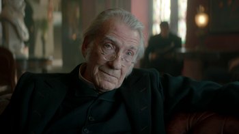 Movie still from “The Alienist” (2018), created by Cary Joji Fukunaga – An old man with glasses sitting in a chair; Close Up shot, Over the shoulder angle