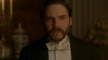 Movie still from “The Alienist” (2018), created by Cary Joji Fukunaga – A person wearing a suit and bow tie; Close Up shot, Low angle