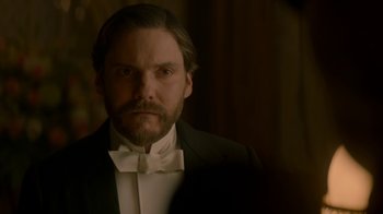 Movie still from “The Alienist” (2018), created by Cary Joji Fukunaga – A man in a suit and bow tie looking at the camera; Close Up shot, Over the shoulder angle