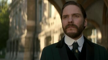 Movie still from “The Alienist” (2018), created by Cary Joji Fukunaga – A man in a suit and tie standing in front of a building; Close Up shot, Low angle