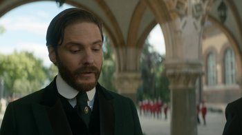 Movie still from “The Alienist” (2018), created by Cary Joji Fukunaga – A man with a beard wearing a suit and tie; Close Up shot, Low angle