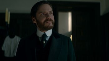 Movie still from “The Alienist” (2018), created by Cary Joji Fukunaga – A man in a suit and tie looking to his left; Close Up shot, Low angle