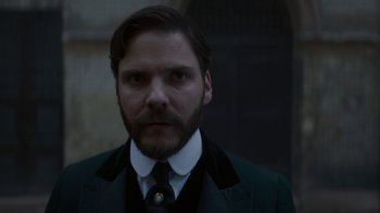 Movie still from “The Alienist” (2018), created by Cary Joji Fukunaga – A person wearing a suit and tie; Close Up shot, Low angle