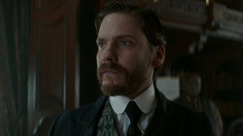 Movie still from “The Alienist” (2018), created by Cary Joji Fukunaga – A person wearing a suit and tie; Close Up shot, Low angle