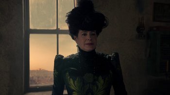 Movie still from “The Alienist” (2018), created by Cary Joji Fukunaga – An older woman wearing a black and green dress; Close Up shot, Low angle