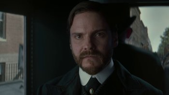 Movie still from “The Alienist” (2018), created by Cary Joji Fukunaga – A person wearing a suit and tie; Close Up shot, Low angle