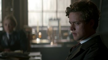 Movie still from “The Alienist” (2018), created by Cary Joji Fukunaga – A man in a suit and tie looking to his left; Close Up shot, Low angle
