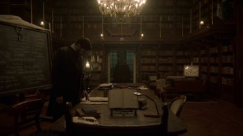 Movie still from “The Alienist” (2018), created by Cary Joji Fukunaga – A man standing in front of a table in a library; Wide shot, High angle