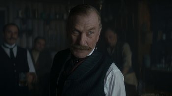 Movie still from “The Alienist” (2018), created by Cary Joji Fukunaga – A man with a beard and mustache wearing a vest and a tie; Close Up shot, Low angle