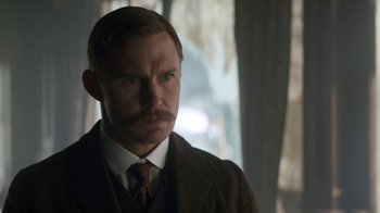 Movie still from “The Alienist” (2018), created by Cary Joji Fukunaga – A man in a suit and tie looking at the camera; Close Up shot, Over the shoulder angle