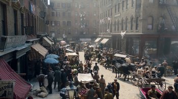 Movie still from “The Alienist” (2018), created by Cary Joji Fukunaga – A crowd of people walking down a street with horse and buggies; Extreme Wide shot, High angle