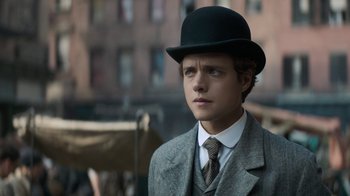 Movie still from “The Alienist” (2018), created by Cary Joji Fukunaga – A young man in a suit and a hat; Close Up shot, Low angle
