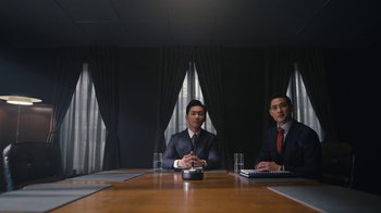 Movie still from “Mr. Robot” (2015), created by Sam Esmail – Two men in suits sitting at a conference room table; Medium shot, Low angle