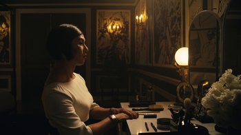 Movie still from “Mr. Robot” (2015), created by Sam Esmail – A woman sitting at a table in front of a lamp; Medium shot, Over the shoulder angle