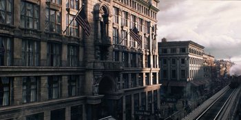 Movie still from “The Alienist” (2018), created by Cary Joji Fukunaga – An old building with flags on the side of the building; Extreme Wide shot, High angle