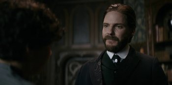 Movie still from “The Alienist” (2018), created by Cary Joji Fukunaga – A man with a long beard standing in front of a fireplace; Close Up shot, Over the shoulder angle