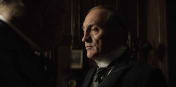 Movie still from “The Alienist” (2018), created by Cary Joji Fukunaga – An older man wearing a suit and a tie; Close Up shot, Low angle