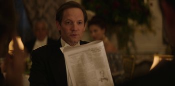 Movie still from “The Alienist” (2018), created by Cary Joji Fukunaga – A man in a suit and tie holding a newspaper; Close Up shot, Over the shoulder angle