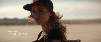 Movie still from “The Bad Batch” (2016), directed by Ana Lily Amirpour – A woman in a baseball cap is standing in the desert; Close Up shot, Over the shoulder angle