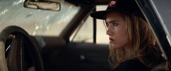 Movie still from “The Bad Batch” (2016), directed by Ana Lily Amirpour – A woman in a hat sitting in the driver's seat of a car; Close Up shot, Low angle