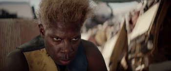 Movie still from “The Bad Batch” (2016), directed by Ana Lily Amirpour – A person with a yellow and blue shirt on; Close Up shot, High angle