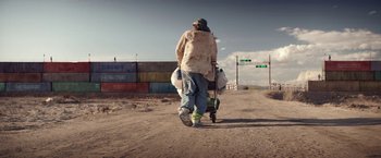 Movie still from “The Bad Batch” (2016), directed by Ana Lily Amirpour – A man is walking down a dirt road; Wide shot, Low angle