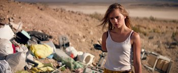 Movie still from “The Bad Batch” (2016), directed by Ana Lily Amirpour – A woman standing in front of a pile of trash; Medium shot, Low angle