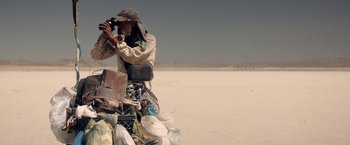 Movie still from “The Bad Batch” (2016), directed by Ana Lily Amirpour – A man standing on top of a pile of trash; Wide shot, Low angle