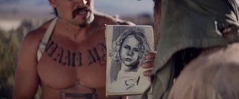 Movie still from “The Bad Batch” (2016), directed by Ana Lily Amirpour – A man holding a drawing of a girl; Close Up shot, Over the shoulder angle