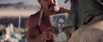 Movie still from “The Bad Batch” (2016), directed by Ana Lily Amirpour – A man holding up a drawing of a girl; Close Up shot, Over the shoulder angle