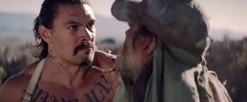 Movie still from “The Bad Batch” (2016), directed by Ana Lily Amirpour – A man with a beard and a mustache is looking at another man with a beard and a mustache; Close Up shot, Over the shoulder angle