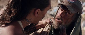 Movie still from “The Bad Batch” (2016), directed by Ana Lily Amirpour – A man with a beard and a tattoo on his face and a man with a beard and a tattoo on his face; Close Up shot, Over the shoulder angle