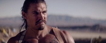 Movie still from “The Bad Batch” (2016), directed by Ana Lily Amirpour – A person with a beard and a mustache; Close Up shot, Over the shoulder angle