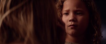 Movie still from “The Bad Batch” (2016), directed by Ana Lily Amirpour – A child's face in a dark room; Close Up shot, Over the shoulder angle