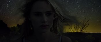 Movie still from “The Bad Batch” (2016), directed by Ana Lily Amirpour – A woman with blonde long hair is looking at the camera; Close Up shot, Low angle